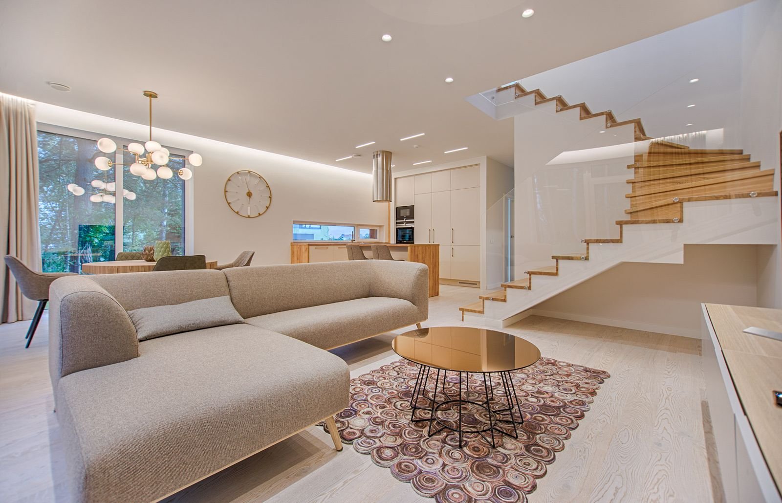 Bright open-plan living room of a premium flat with a wooden staircase