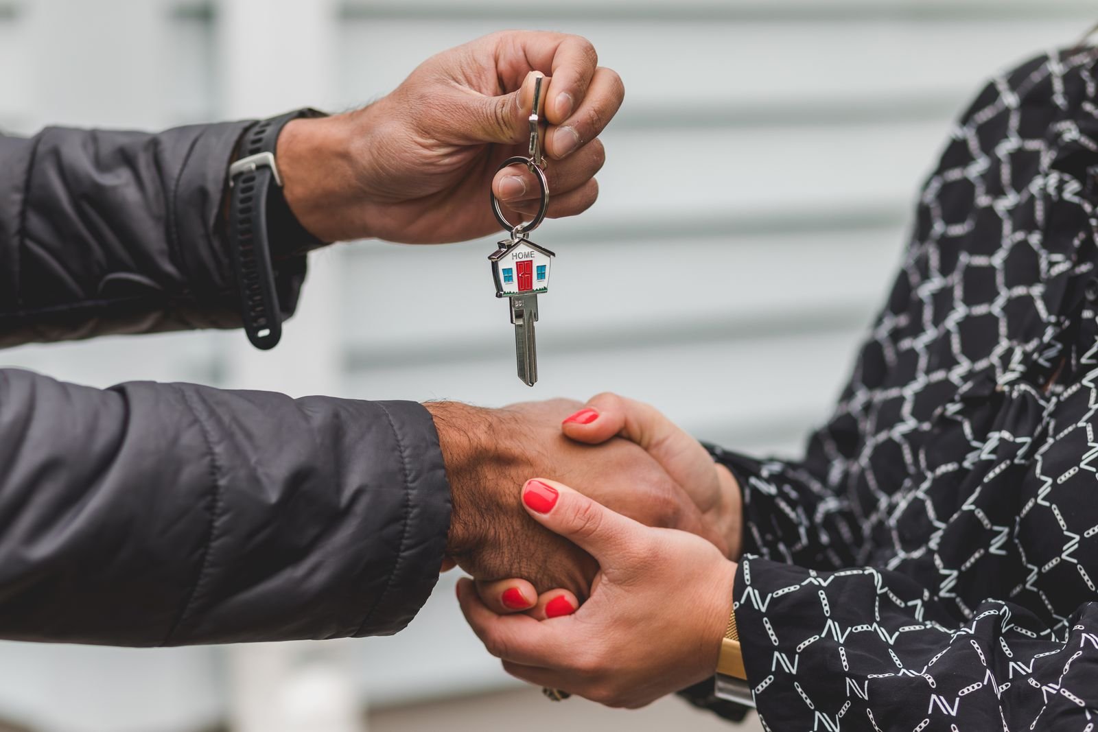 Agent handing over a house-shaped key with a handshake