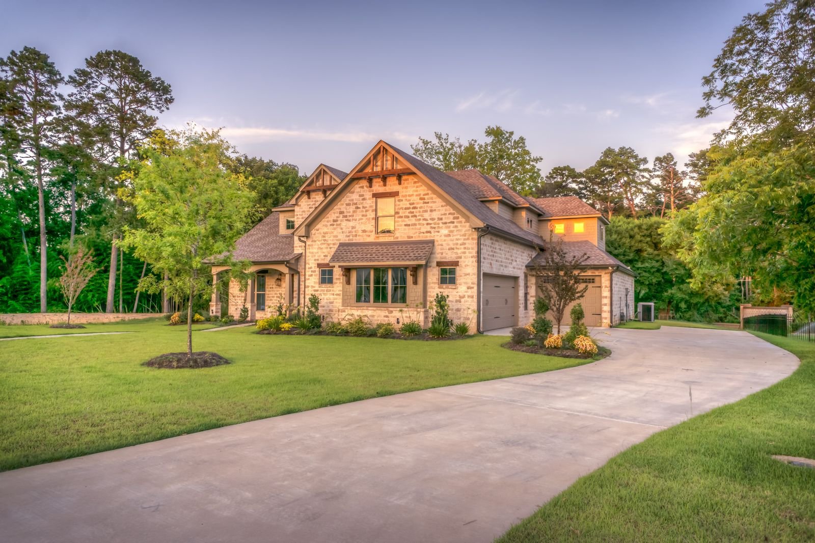 Stone-clad residential bungalow at golden hour with a landscaped driveway
