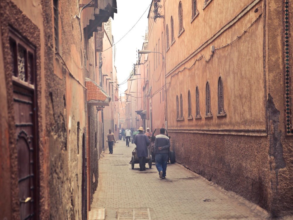 A busy street in Marrakech with people walking between ochre buildings