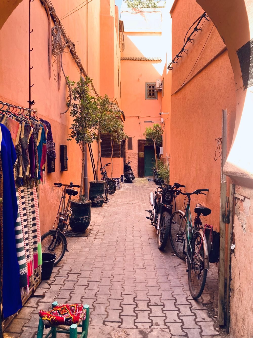 A sunlit alley in a Moroccan medina, ochre walls and patterned doorways