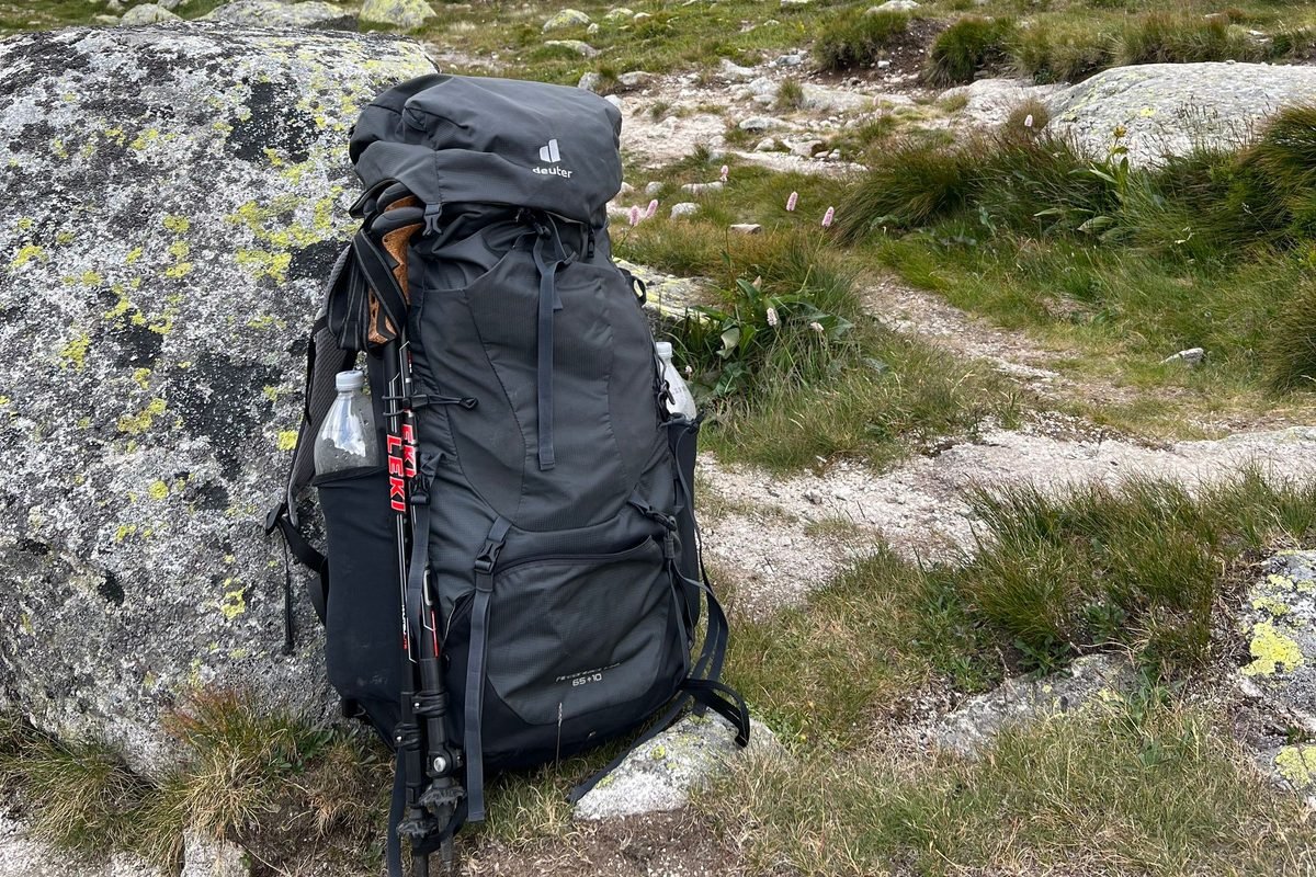 A loaded hiking backpack resting on a rock beside a mountain trail