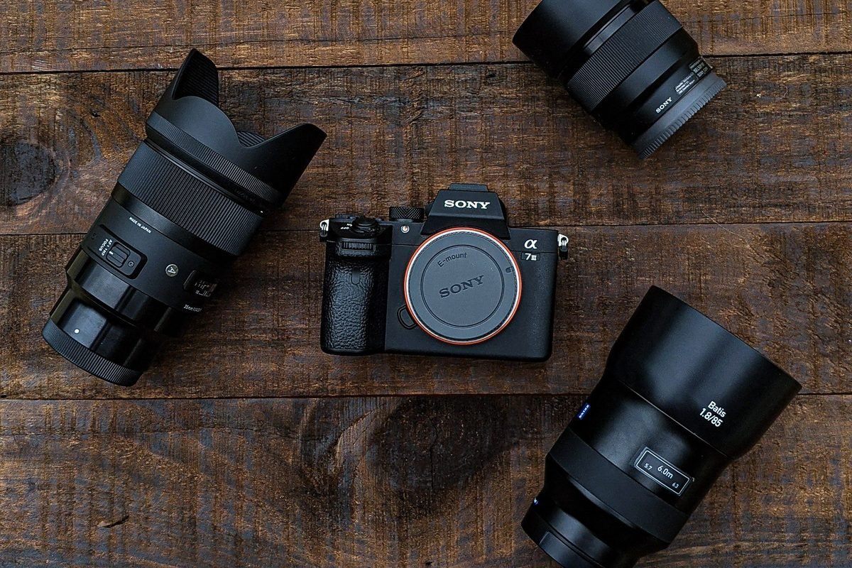 A camera body and several lenses laid out on a flat surface