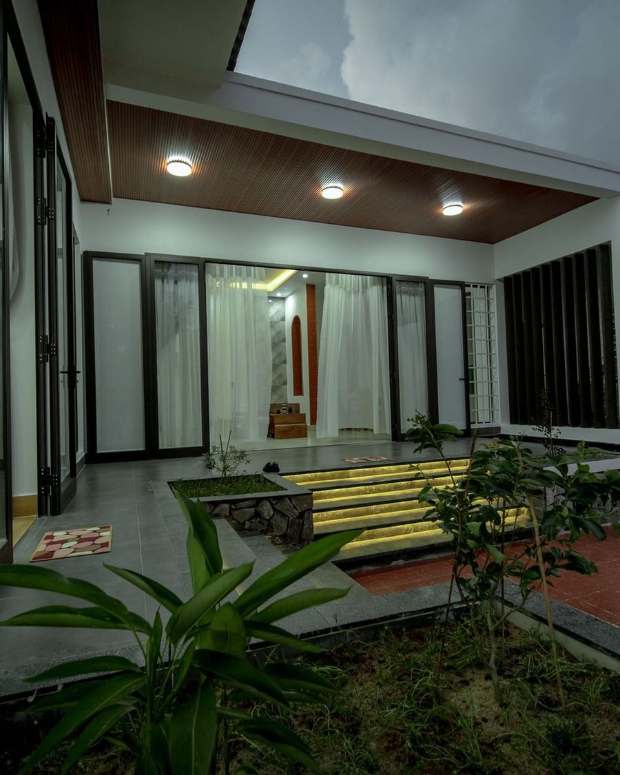 Planted internal courtyard of a private house, framed by sliding glass doors and a shaded verandah
