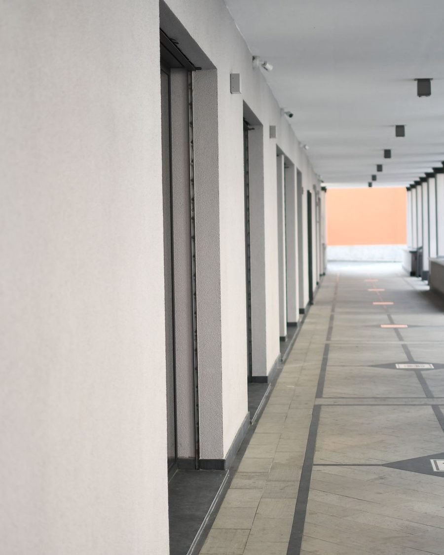 Long naturally lit school corridor with deep window reveals and a warm-toned end wall