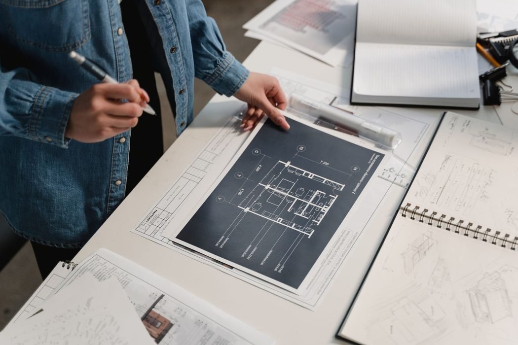 Two architects reviewing a printed floor plan and sketch sheets across a studio table