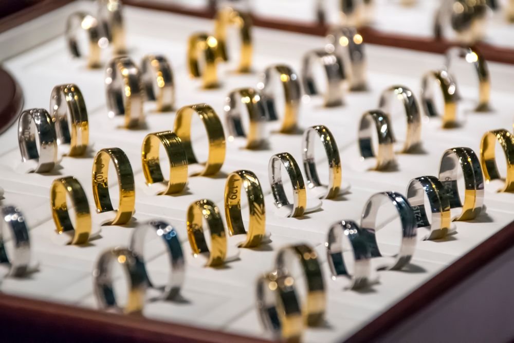 Tray of plain gold and white-gold wedding bands lined up in showroom display case