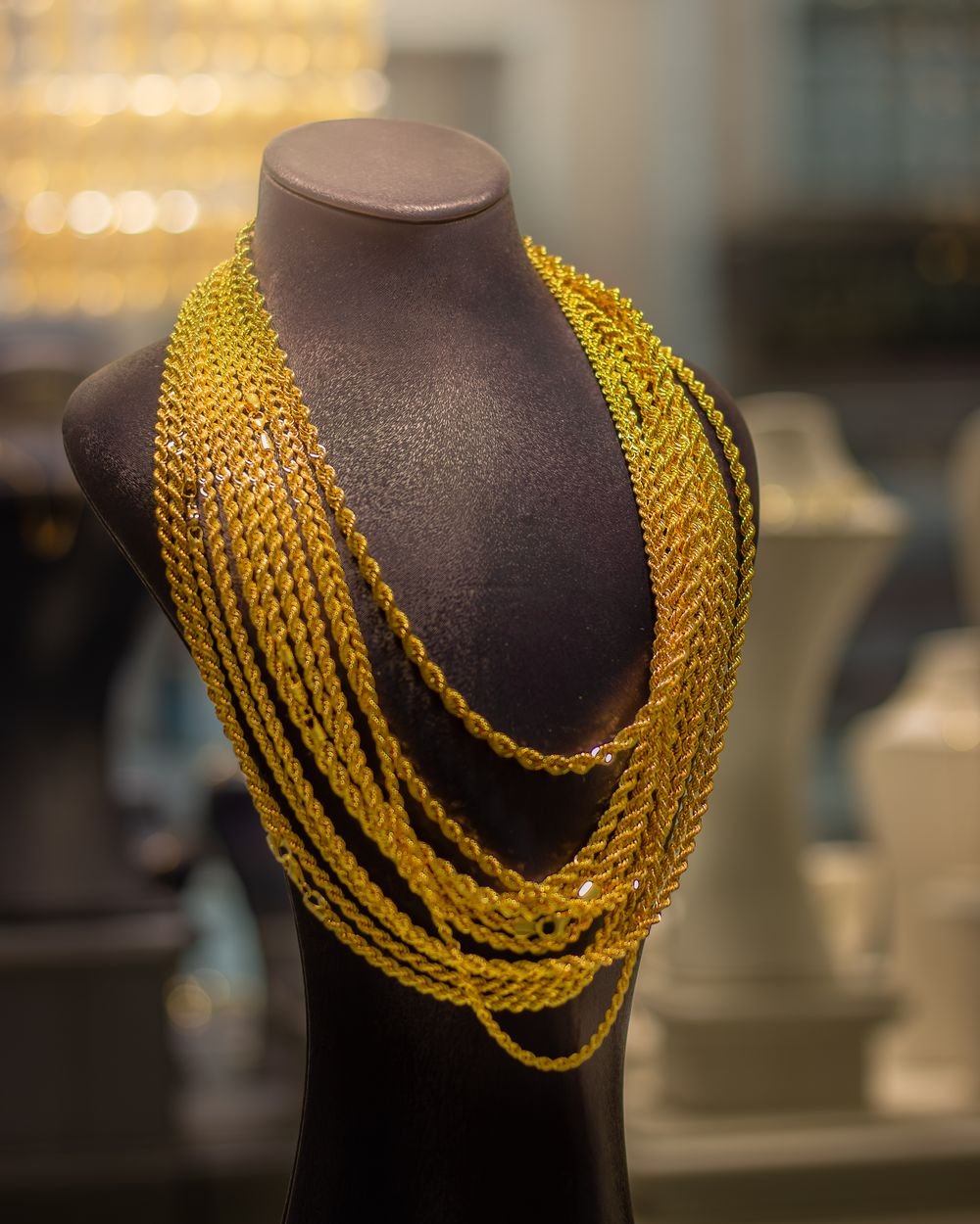 22-karat gold rope chains hanging on dark display bust inside showroom