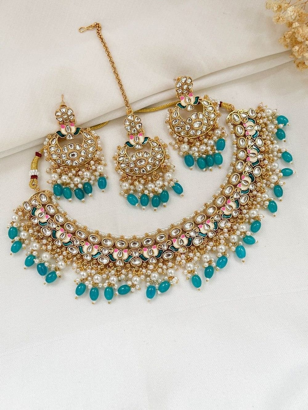 Kundan necklace set with matching chandbali earrings and maang tikka, strung with pearls and turquoise drops on ivory cloth